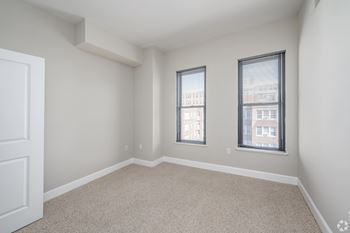 A room with two windows and a carpeted floor.